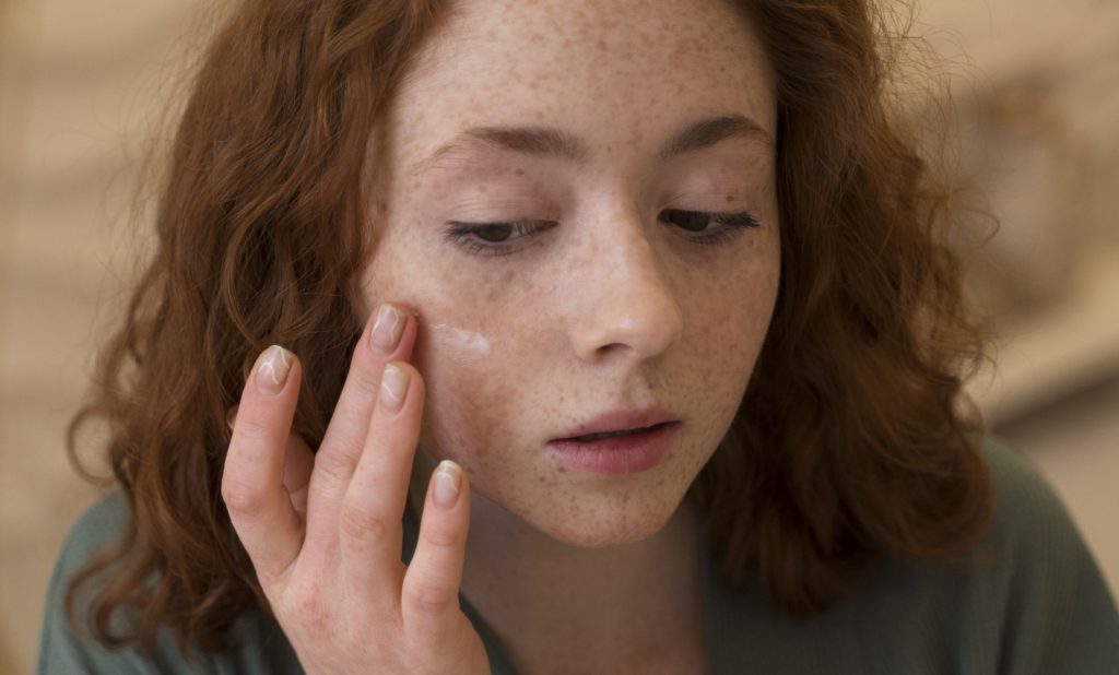 Mujer usando producto dermatológico para el cuidado facial
