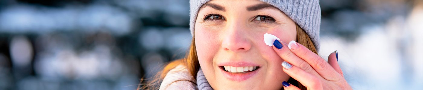 Mujer joven con ropa de invierno aplicándose producto en la piel.psd